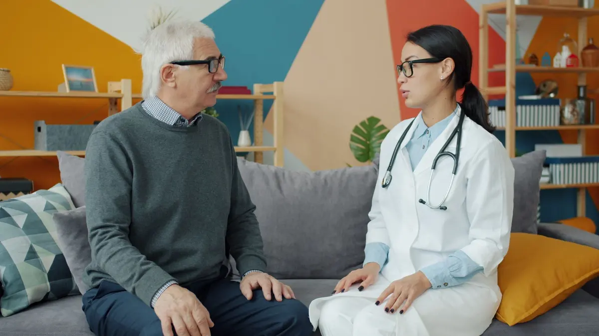Médica conversando com paciente idoso durante a consulta