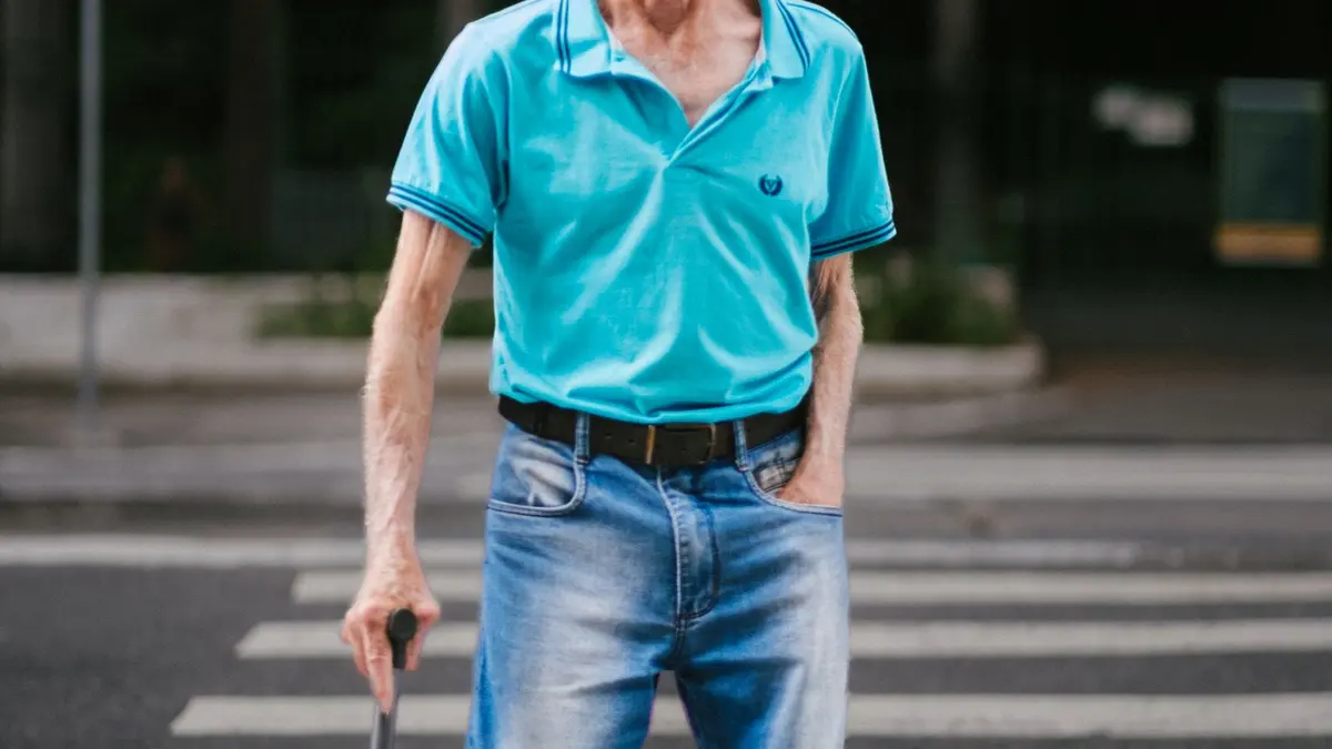 Homem idoso atravessando a rua com o apoio de uma bengala
